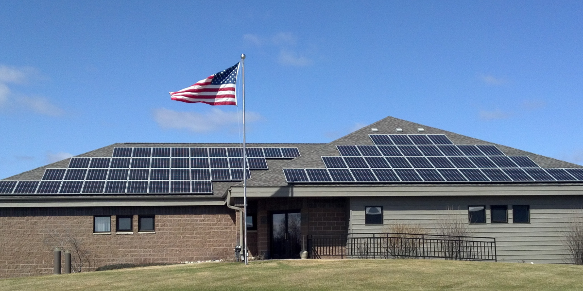 Building with rooftop solar panels and an American flag